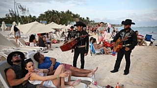 Dos mariachis hablan con turistas en Playa del Carmen, en el estado mexicano de Quintana Roo.