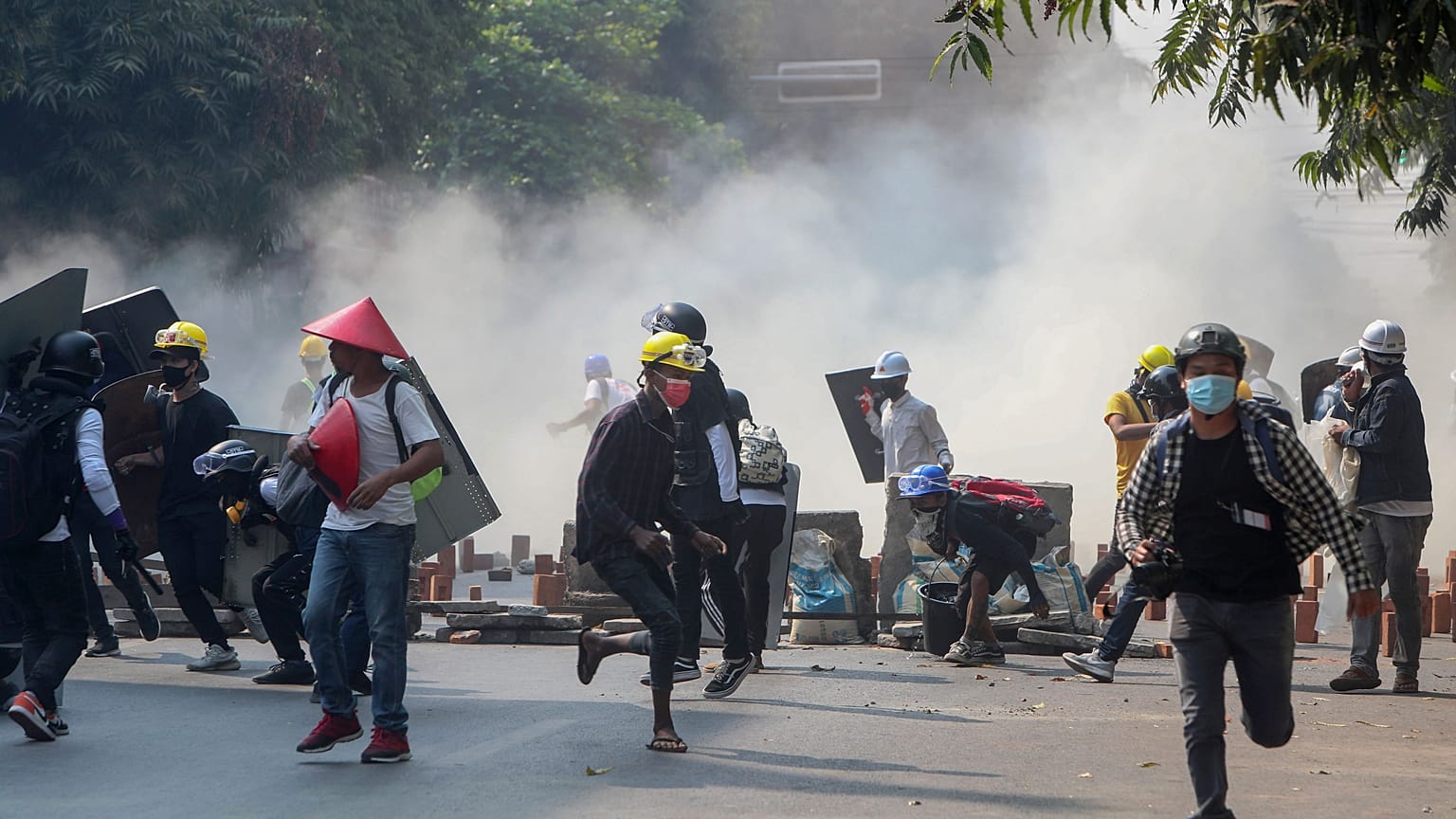 Anti-coup protesters run from teargas and charging riot police and soldiers in Mandalay, Myanmar on Wednesday