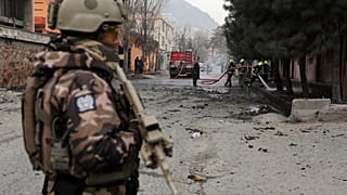Katona védi a tűzoltókat, akik egy bombatámadás helyszínén dolgoznak