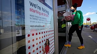 In this Sept. 30, 2020, file photo, a passerby walks past a hiring sign while entering a Target store in Westwood, Mass.