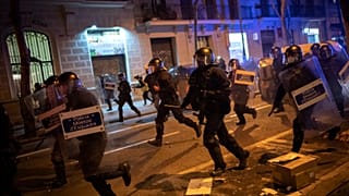 FILE PHOTO: Police officers run during clashes following a protest condemning the arrest of rap singer Pablo Hasel in Barcelona, Spain, Tuesday, Feb. 23, 2021.