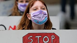 Women, wearing masks against the COVID-19 infection that read "Feminist Solidarity", hold banners during a protest in Bucharest, Romania, Sunday, Oct. 25, 2020.