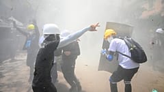 Protesters react after tear gas is fired by police during a demonstration against the military coup in Yangon on March 7, 2021.