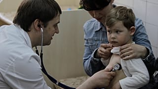 Врач-педиатр Федор Лапий осматривает ребенка перед введением вакцины в Киеве, Украина. 23 апреля 2013 г.