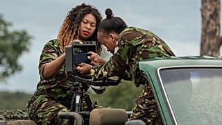 Two rangers set up a mobile camera on the back of a 4x4.