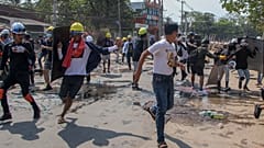 Anti-coup protesters retreat from the frontlines after riot policemen fire sound-bombs and rubber bullets in Yangon, Myanmar, Thursday, March 11, 2021. 