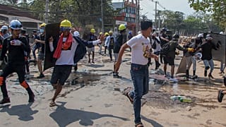 Anti-coup protesters retreat from the frontlines after riot policemen fire sound-bombs and rubber bullets in Yangon, Myanmar, Thursday, March 11, 2021. 