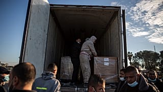 عمال فلسطينيون يفرغون شحنة لقاح Sputnik V الأولى عند وصولها إلى قطاع غزة، 21 فبراير 2021.