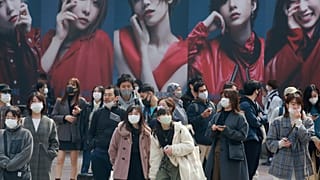 People wearing face masks to protect against the spread of the coronavirus wait at an intersection in Tokyo, Tuesday, March 9, 2021. (AP Photo/Koji Sasahara)