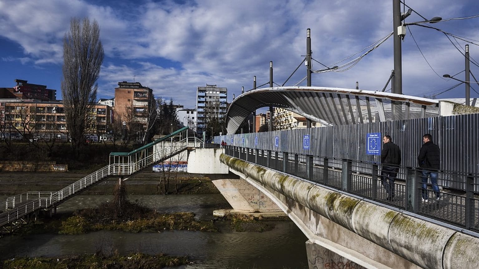 People walk on the main bridge of the town of Mitrovica on February 13, 2016.