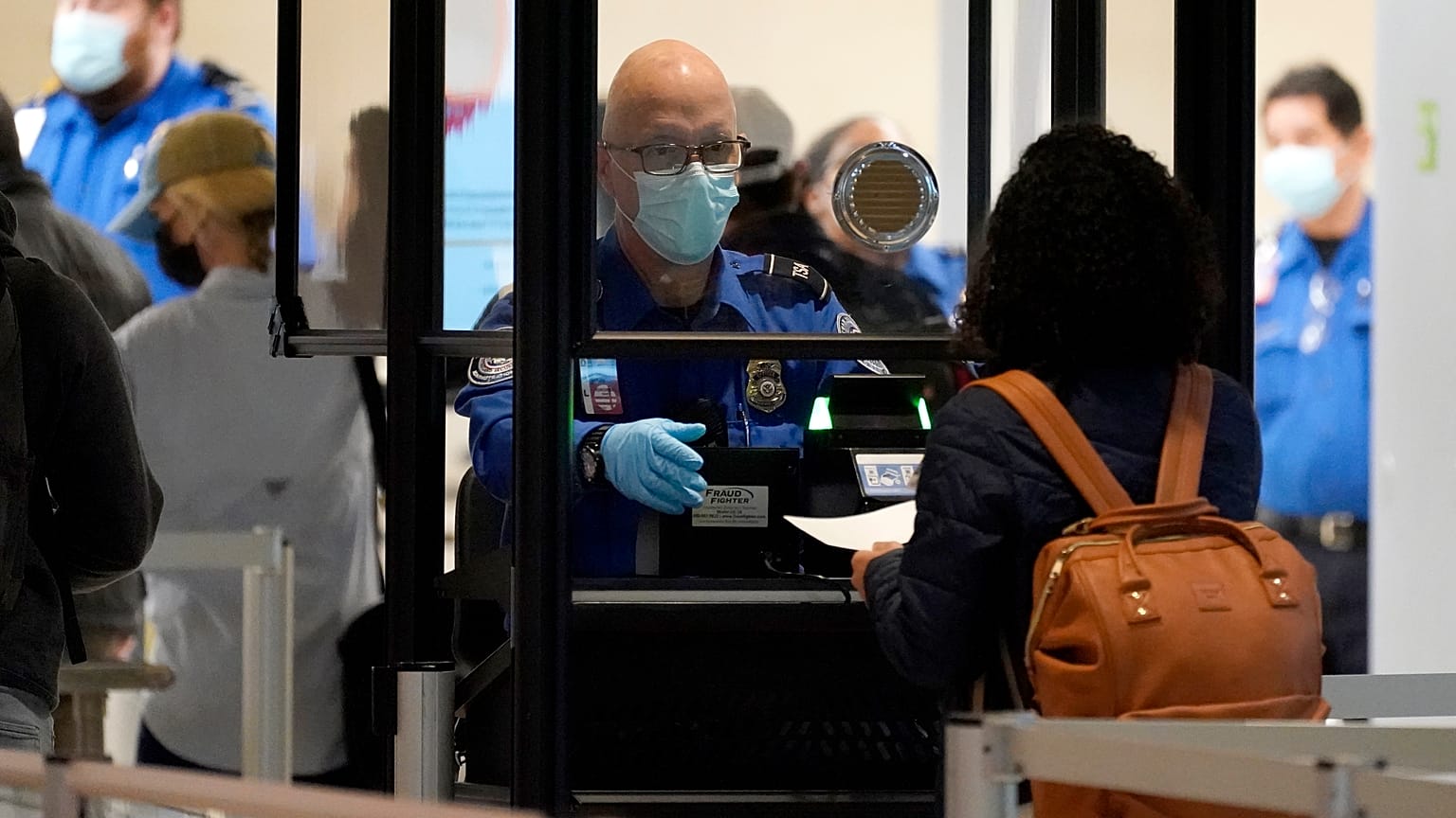 A TSA agent assists a traveller at a security checkpoint at Love Field Airport, Dallas, 24 Nov 2020 