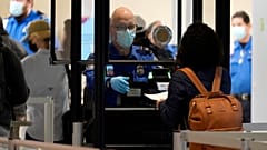 A TSA agent assists a traveller at a security checkpoint at Love Field Airport, Dallas, 24 Nov 2020 