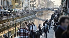 People stroll in the Navigli popular area Milan, Italy, Saturday, March 13, 2021.