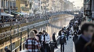 People stroll in the Navigli popular area Milan, Italy, Saturday, March 13, 2021.