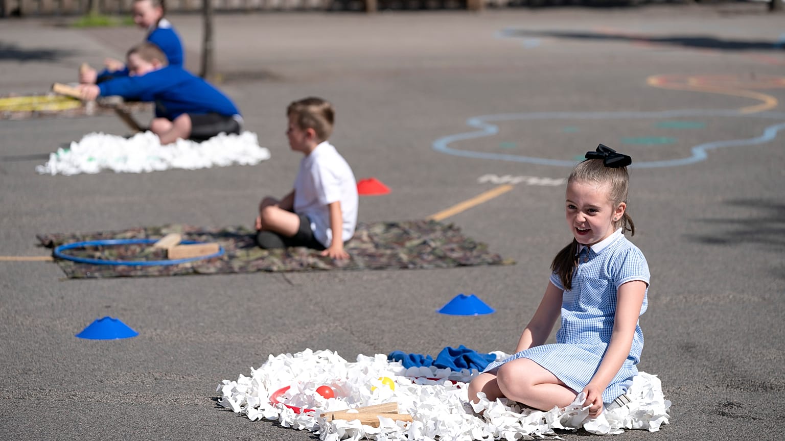 Children at Seymour Road Academy sit in designated areas in the playground during the coronavirus outbreak in Manchester, England, Wednesday May 20, 2020.