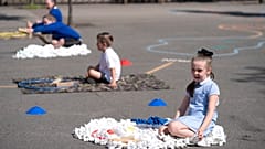 Children at Seymour Road Academy sit in designated areas in the playground during the coronavirus outbreak in Manchester, England, Wednesday May 20, 2020.