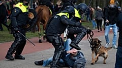 Dutch riot police kick a man during a demonstration to protest government policies including the curfew, lockdown and coronavirus related restrictions in The Hague.