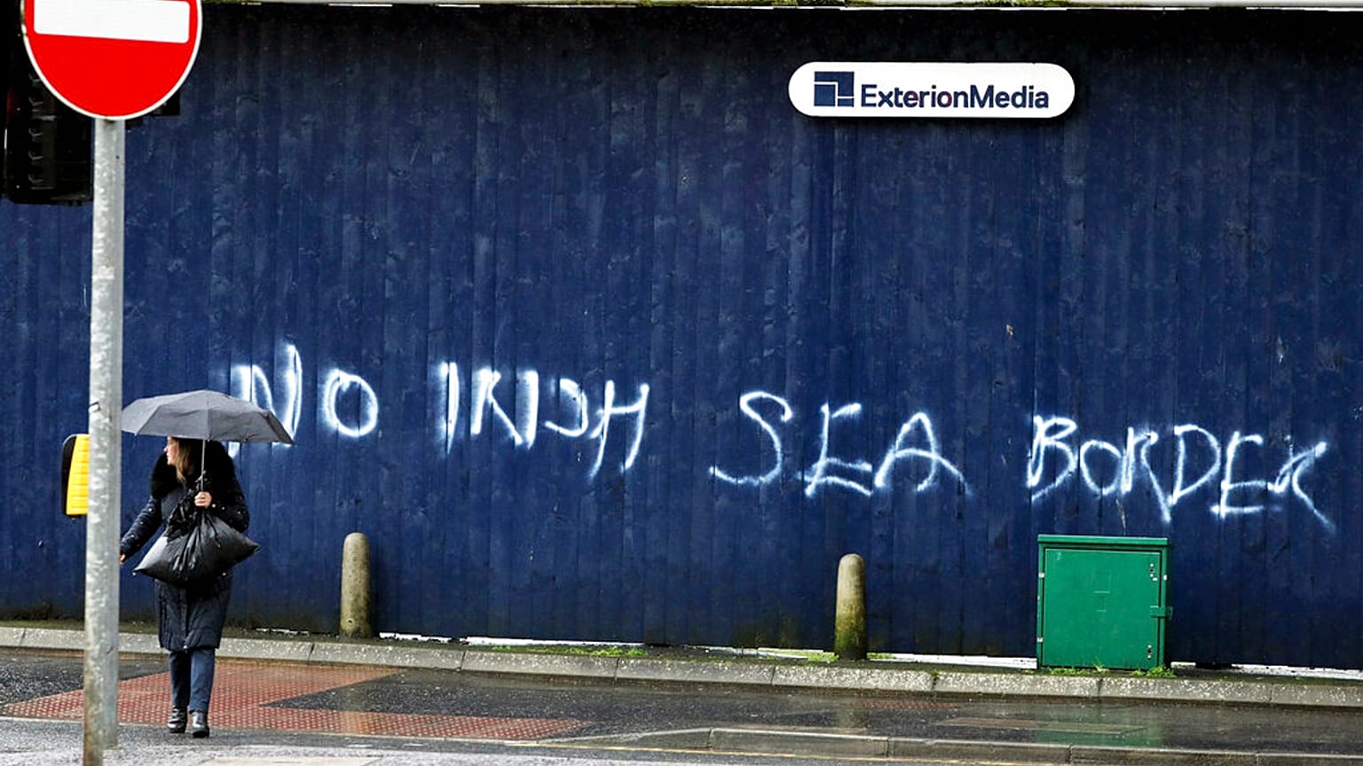 A woman walks past past graffiti with the words 'No Irish Sea Border' in Belfast city centre, Northern Ireland, Wednesday, Feb. 3, 2021.