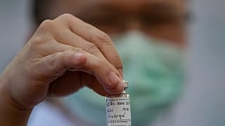 Медицинский работник держит бутылочку с вакциной AstraZeneca.