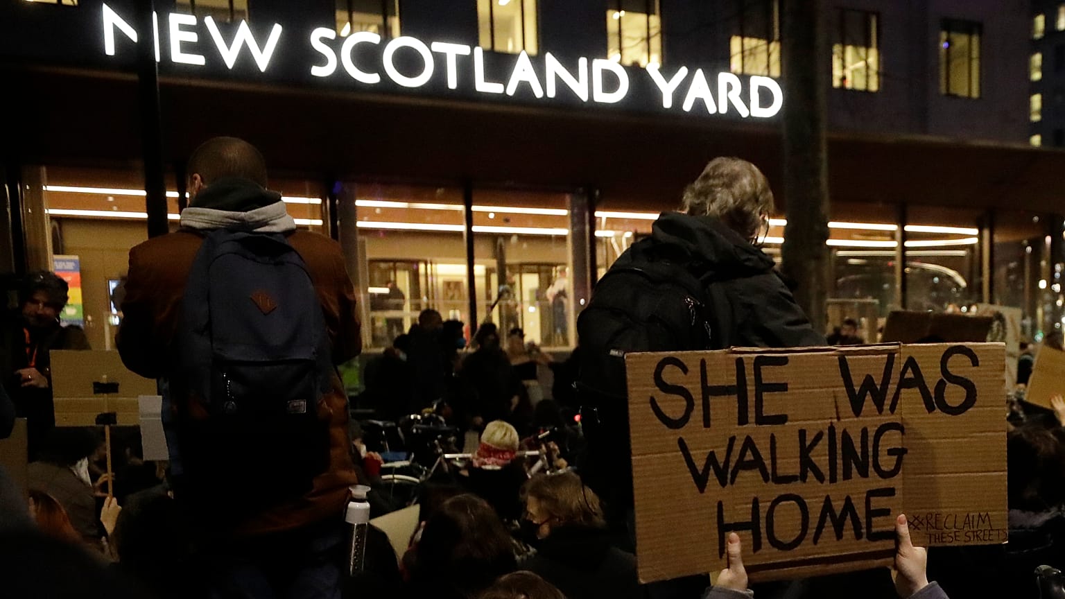 People hold signs outside New Scotland Yard during a march to reflect on the murder of Sarah Everard, in London, March 15, 2021. 