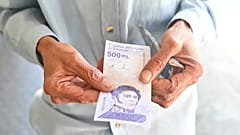 Un hombre muestra un billete de 200.000 bolívares