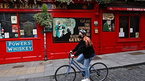 A cyclist passes a closed bar in the Temple bar area of Dublin, Ireland, Wednesday, Oct. 21, 2020