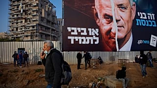 فلسطينيون ينتظرون المواصلات تحت لوحة إعلانية لحملة الانتخابات الإسرائيلية. 2021/03/14