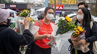 Roula AbiSamra, center, and Chelsey (last name withheld), right, prepare to lay flowers bouquets at a makeshift memorial outside of the Gold Spa in Atlanta, Wednesday.