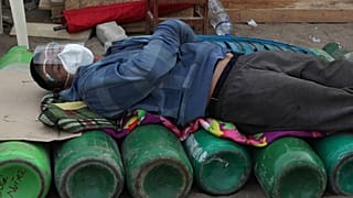 Um homem dorme sobre garrafas de oxigénio, um bem escasso agora no Peru