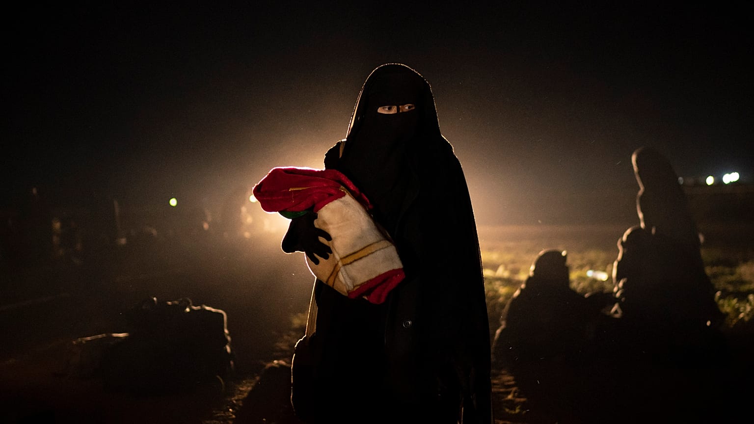 Una donna sfollata da uno degli ultimi territori in mano allo Stato islamico, nel deserto alle porte di Baghouz, in Siria, mentre viene controllata dalle forze siriane