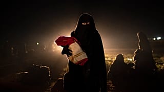 Una donna sfollata da uno degli ultimi territori in mano allo Stato islamico, nel deserto alle porte di Baghouz, in Siria, mentre viene controllata dalle forze siriane
