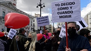 A man holds a placard reading "I decide when and how to die" during a demonstration in support of a law legalising euthanasia in Madrid on March 18, 202