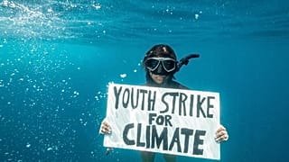 Climate activist Shaama Sandooyea holds a placard reading: “Nou Reklam Lazistis Klimati” (Mauritian creole for “We Demand Climate Justice”)