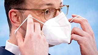 Der deutsche Gesundheitsminister Jens Spahn setzt sich nach einer Pressekonferenz seine FFP-2 -Maske auf