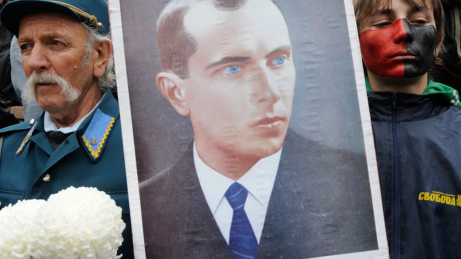 A man dressed in Ukrainian insurgent army uniform seen by a young supporter of the Ukrainian Insurgent Army holds a portrait of Stepan Bandera.
