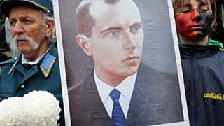 A man dressed in Ukrainian insurgent army uniform seen by a young supporter of the Ukrainian Insurgent Army holds a portrait of Stepan Bandera.