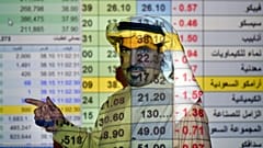 یک کارگزار بورس عربستان در حال توضیح در مورد روند قیمت سهام شرکت‌ها از جمله آرامکو