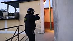 Agente da polícia com arma apontada entra num corredor de uma favela em Los Teques