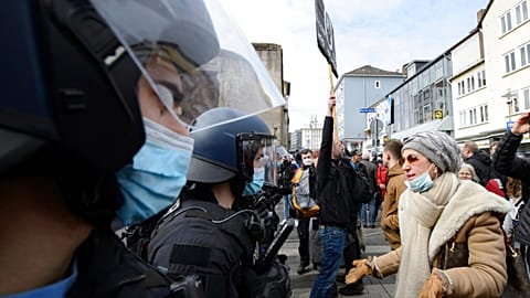 A woman speaks to police officers on duty at a rally under the motto "Free citizens Kassel - basic rights and democracy" in Kassel, Germany, Saturday, March 20, 2021.