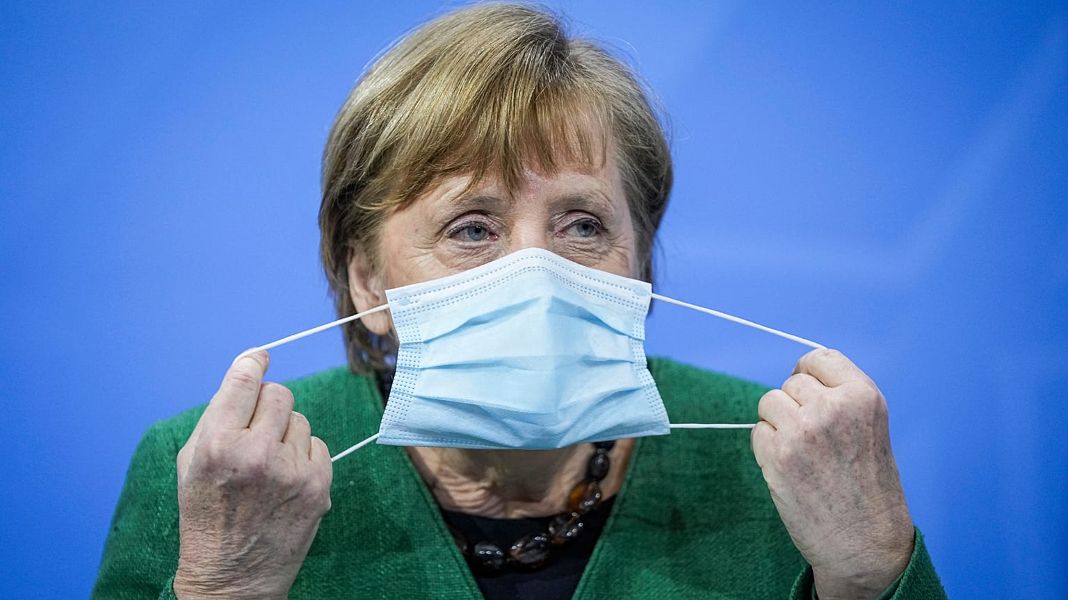 German Chancellor Angela Merkel removes her mask at the start of a press conference in Berlin, Tuesday, March 23, 2021.