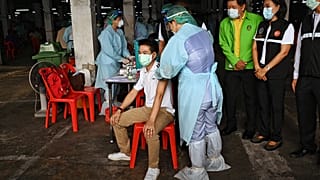 يراقب المسؤولون رجلاً يتلقى لقاح كورونافاك- الصين