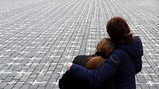 People observe a minute of silence as thousands of crosses are painted at the Old Town Square, to mark the 1-year anniversary of the death of first Czech COVID-19 patient