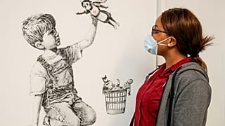 A member of staff at University Hospital Southampton poses with Banksy's "Game Changer" artwork. May 7, 2020