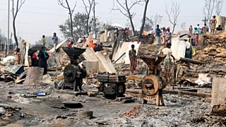 Rohingya refugees stand by remains of Monday's fire at a refugee camp in Balukhali, southern Bangladesh, Tuesday, March 23, 2021.