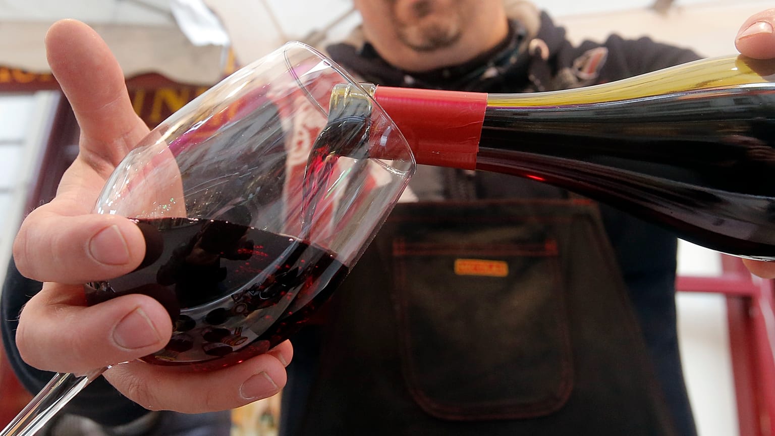 A wine storekeeper pours red wine in a glass during a presentation in a wine shop in Paris, Thursday Nov. 20, 2014