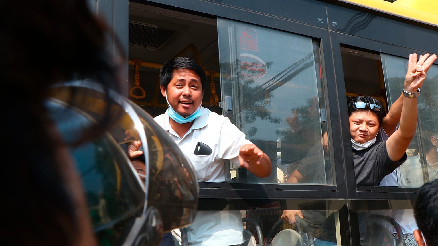An arrested protester flashes the three-fingered salute while onboard a bus getting out of Insein prison to go to an undisclosed location on March 24, 2021 in Yangon, Myanmar 