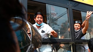 An arrested protester flashes the three-fingered salute while onboard a bus getting out of Insein prison to go to an undisclosed location on March 24, 2021 in Yangon, Myanmar 
