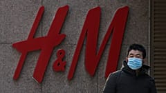 A man wearing a face mask walks by a Swedish fashion brand H&M store outlet in Beijing, March 25, 2021. 