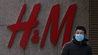 A man wearing a face mask walks by a Swedish fashion brand H&M store outlet in Beijing, March 25, 2021.