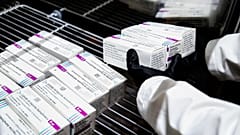 A health worker places packages containing doses of the AstraZeneca vaccine inside a fridge upon their arrival at a vaccination centre in Rome. February 9, 2021 